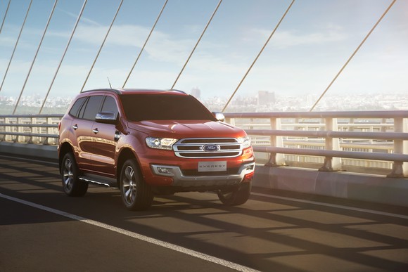 A red Ford Everest is shown driving across a bridge. 