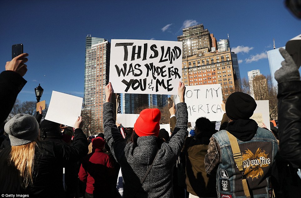 Protesters are seen with signs during the rally in New York's Battery Park on Sunday afternoon against Trump's executive order