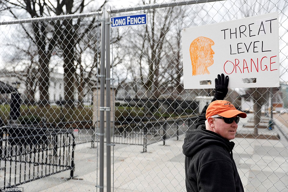 An activist holds a sign outside the White House to protest President Donald Trump's 'Muslim ban' and changes to refuge policy