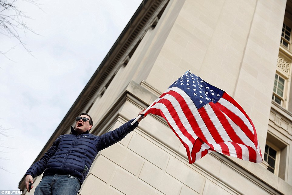 A man is seen rallying the crowd in Washington DC on Sunday while holding an American flag in the air 