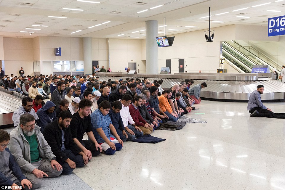 People gather to pray in baggage claim at Dallas International Airport during a protest against Donald Trump's travel ban