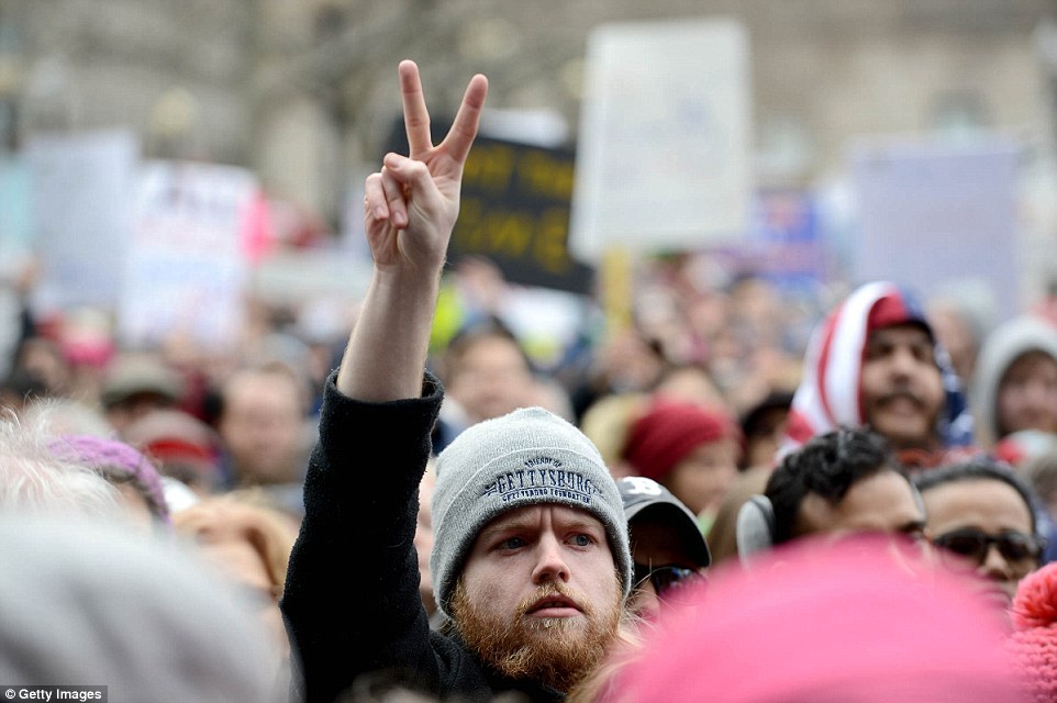 People gather in Copley Square to protest the Muslim immigration ban enacted by President Trump, including one man who is giving the peace symbol