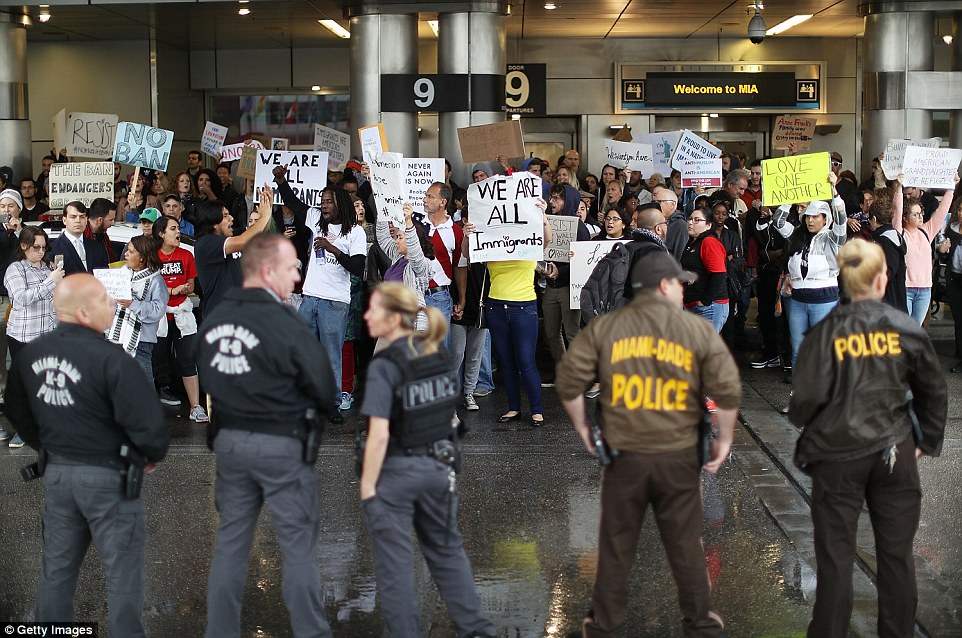 Police officers stood by as protesters gathered outside Miami International Airport to voice their disagreement on Sunday