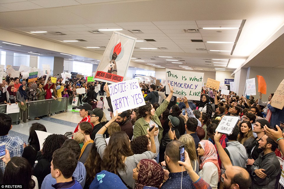 People chanted and held signs as they protested against the ban at Dallas/Fort Worth Airport's international arrivals gate