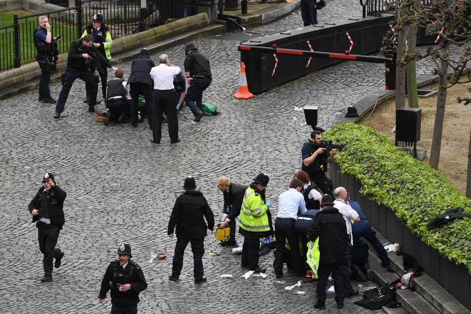 Emergency services treat two people - thought to be the attacker and injured cop - outside Parliament following the attack