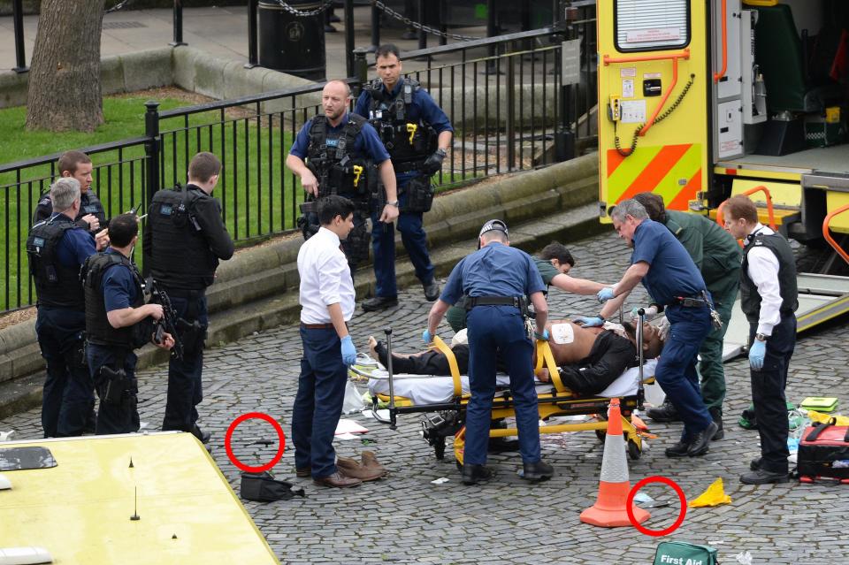 An image from the scene shows two knives on the ground as paramedics treat a suspect